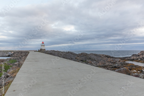 White lighthouse with red roof in Norway. Norwegian scenic landscape with a tall white lighthouse. Lighthouse on the background of harsh Scandinavian nature. Norway.