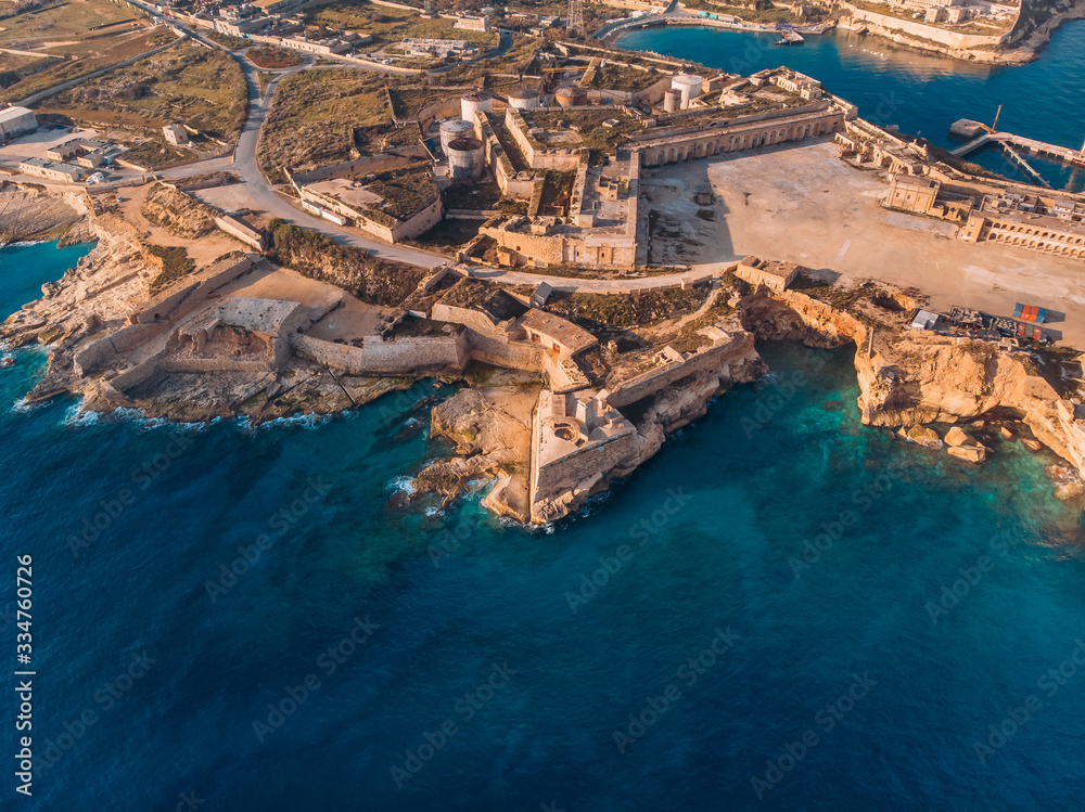 Ancient stone military fort Malta island made of brick rocks on shore blue sea with view city Valetta, aerial top view
