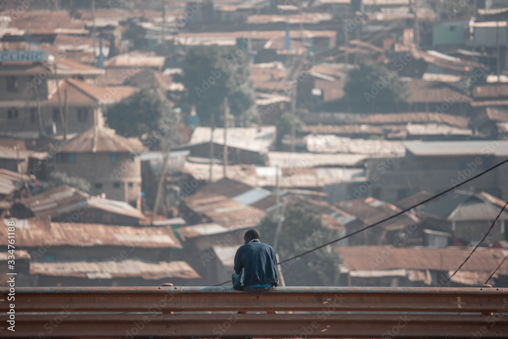 Man sits looking out over slum in Kibera, Kenya