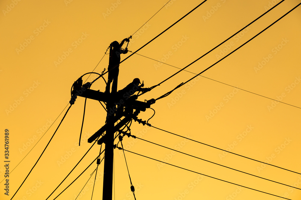 silhouette electrician working on electric power pole