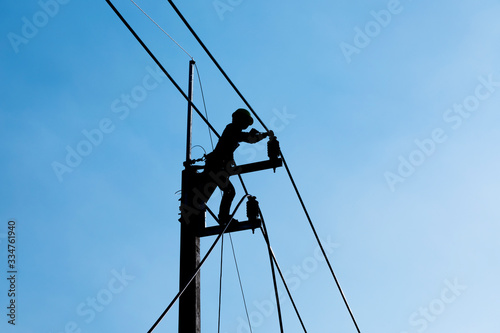 silhouette electrician working on electric power pole