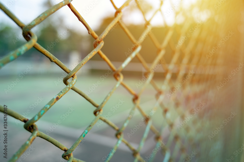 Fototapeta premium Closeup of green metal fence on blurred tennis knock board court