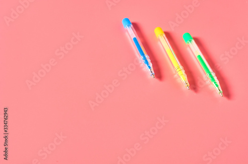 Three colorful pens on pink desk. Education concept