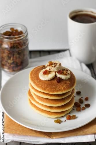 pancakes with banana on white plate and cup of coffee.  Breakfast in the kitchen