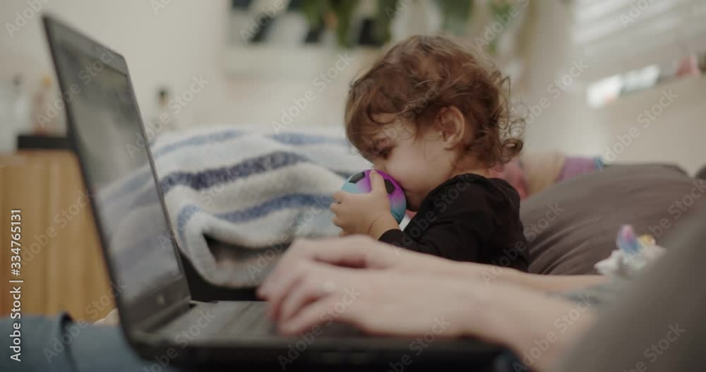 Mother working from home with toddler during COVID-19 lockdown. Real life footage, not staged. Mother working from home with toddler during COVID-19 lockdown. Real life footage, not staged.