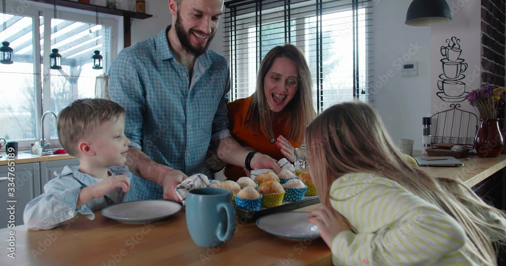 Happy family time concept, young father brings in holiday muffins to celebrate with mother and cute children slow motion Happy family time concept, young father brings in holiday muffins to celebrate with mother and cute children slow motion