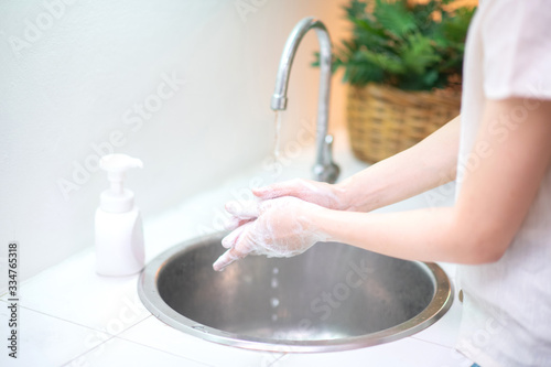 Close up of woman washing hand with liquid soap in the kitchen at home,prevent from corona virus or covid-19,Hygiene concept