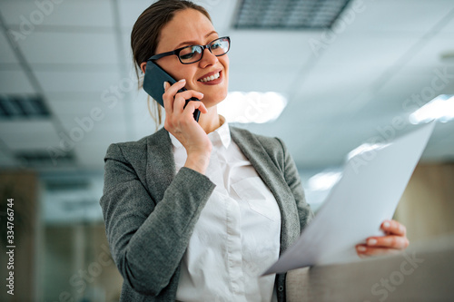 Businesswoman talking on the phone and holding a document, close-up.