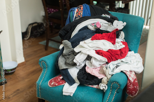 Pile of laundry of clothes on colorful chair in home