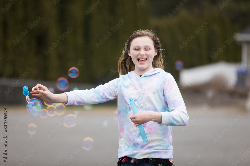 Happy pre-teen girl playing outside with colorful bubbles Happy pre-teen girl playing outside with colorful bubbles