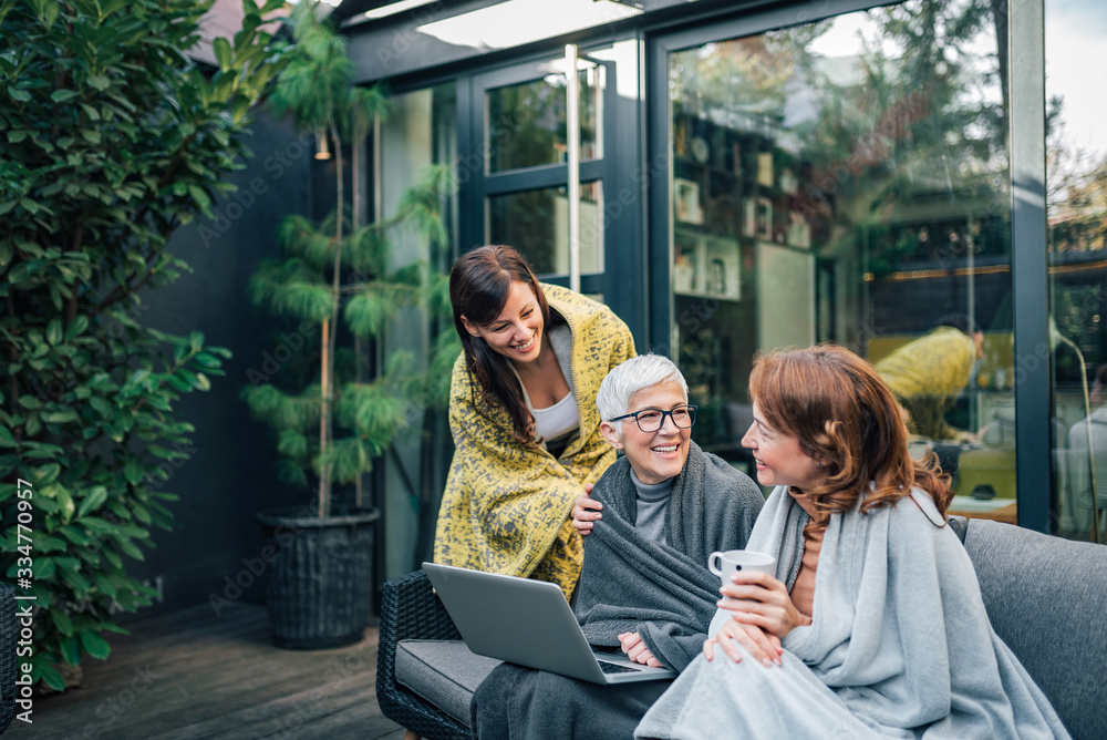 Fototapeta premium Happy family time. Three women of different age relaxing at modern home garden.