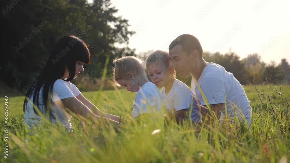 Happy family, mom and dad with children have fun outdoors in the Park. A group of children brother and sister using a smartphone playing a game. Happy family, mom and dad with children have fun outdoors in the Park. A group of children brother and sister using a smartphone playing a game.