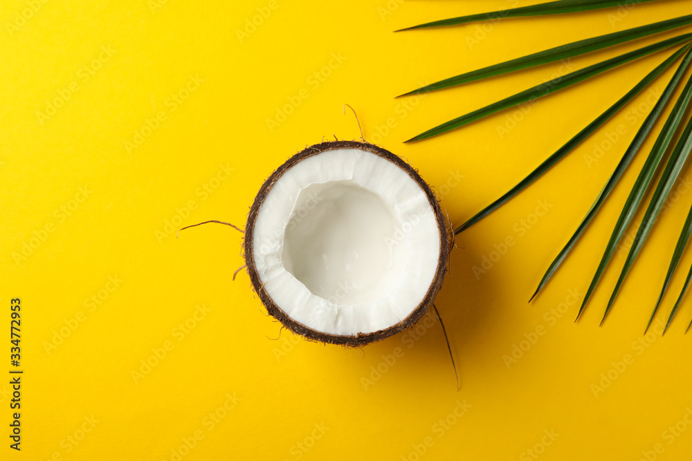 Half of coconut and palm leaf on yellow background, top view Half of coconut and palm leaf on yellow background, top view
