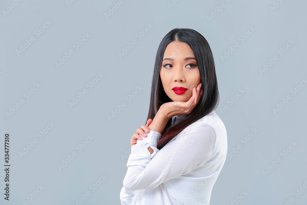 Young Asian woman with beautiful hair on grey background Young Asian woman with beautiful hair on grey background