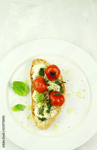 Concetto di cibo sano. Una fetta di pane con mozzarella fresca, pomodori e foglie di basilico isolati sul piatto bianco. Vista dall'alto, copia spazio.