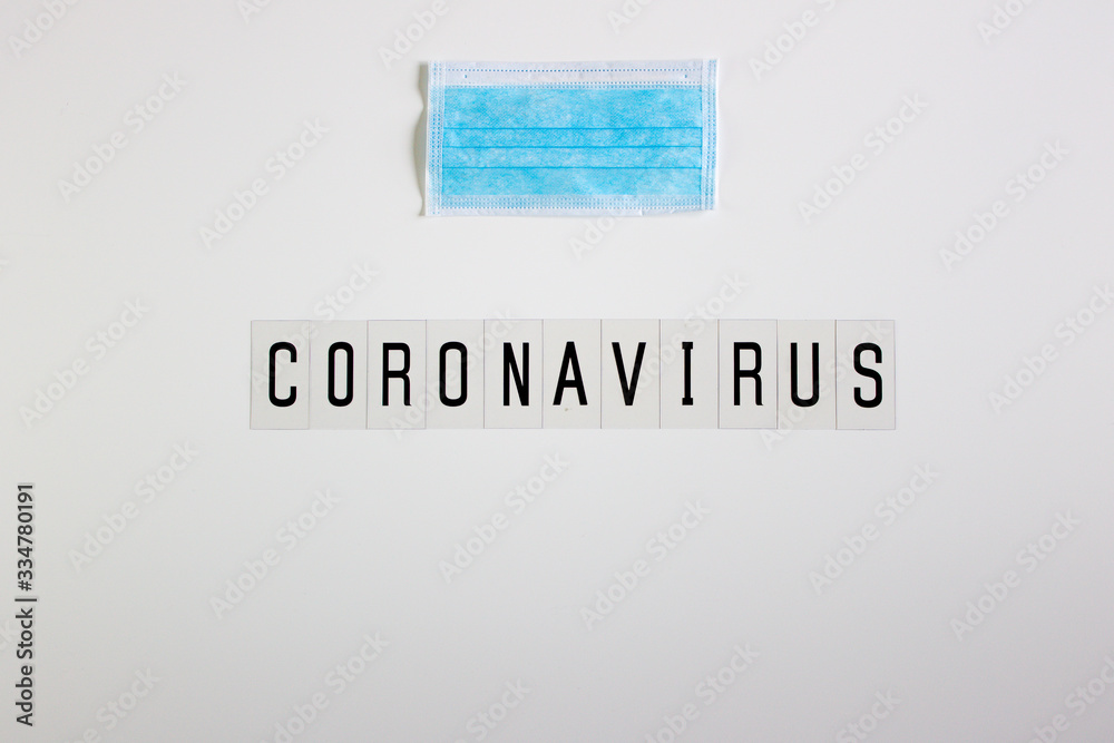 Fototapeta premium Coronavirus word in black on white background, with essential mask for protection of people.