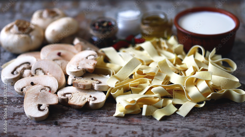 Fototapeta premium Raw pasta, mushrooms, cream and spices. Products for the preparation of mushroom pasta with cream. Mushrooms pasta recipe.