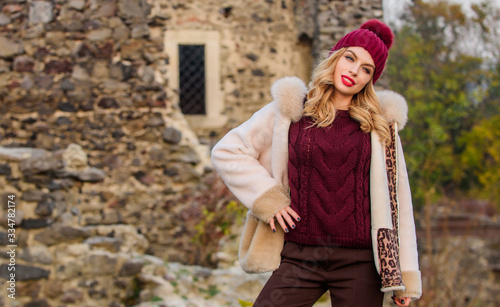 Hit of season. Stay warm and fashionable. Woman wear furry coat. Winter clothes. Wardrobe for cold weather. Girl stand near stone ruins. Fancy chic coat. Natural wool sheepskin coat. Fur on hood © be free