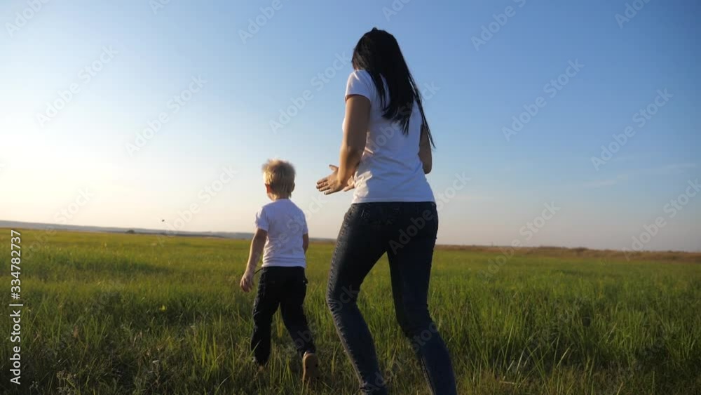 A young mother plays with a child on the street. A woman runs after a small cheerful son. Happy family having fun outdoors. A young mother plays with a child on the street. A woman runs after a small cheerful son. Happy family having fun outdoors.
