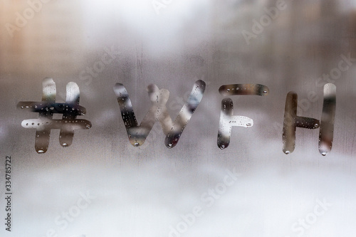 hashtag word wfh - work from home handritten on wet window glass at cloudy weather photo