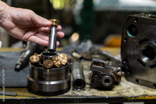 Professional mechanic man holding piston of the hydraulic pump to inspection and repair maintenance heavy machinery