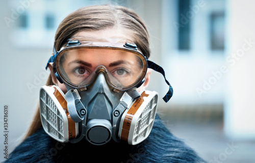 Young woman wearing full face respirator protective mask and goggles, extreme coronavirus protection concept photo