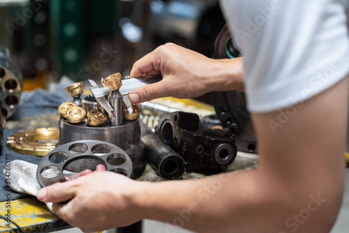 Professional mechanic man holding piston of the hydraulic pump to inspection and repair maintenance heavy machinery