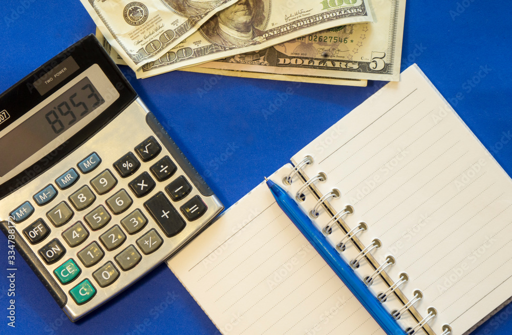 the workspace on the table, where there is a calculator and banknotes for calculating savings, finances, accounting expenses of the accounting department of an enterprise or bank the workspace on the table, where there is a calculator and banknotes for calculating savings, finances, accounting expenses of the accounting department of an enterprise or bank
