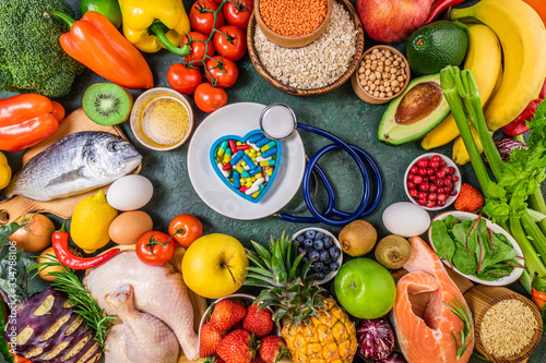 Fototapeta Naklejka Na Ścianę i Meble -  Background of healthy food. Fresh fruits, vegetables, meat and fish on table. Food to boost immunity. Choice healthy food or medicine pills concept. Top view, copy space