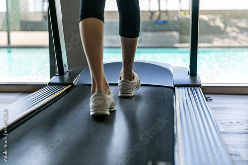 Legs of woman running on a treadmill in gym