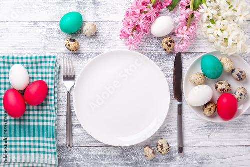 Spring table setting. Green mint plate, easter eggs, hyacinth and silver cutlery on wooden background. Copy space. Top view