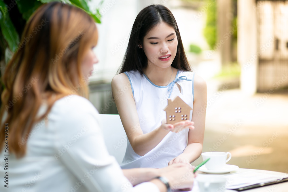 Two young women talking about new home in cafe. Working with home model concept. Two young women talking about new home in cafe. Working with home model concept.