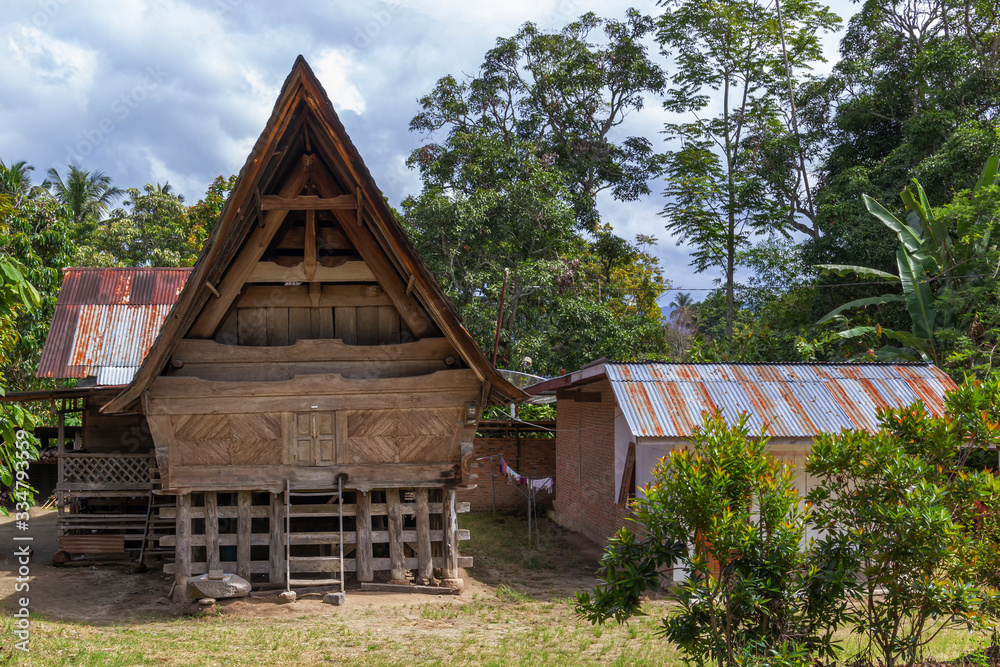 Old wooden house in traditional indonesian style on a background of blue sky with clouds on a sunny day