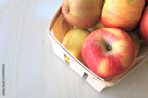 Basket of fresh apples on wood table with place for text