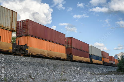 Train long freight passing with container loading on railway in valley
