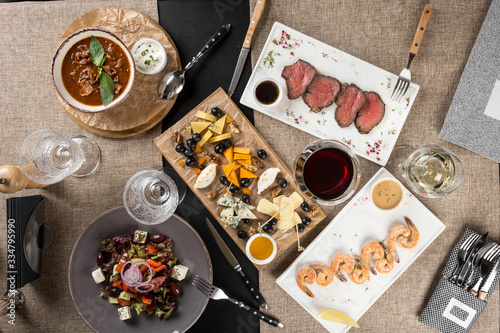dinner table with shrimp, roast beef, salad, cheese platter and wine served at home or at restaurant