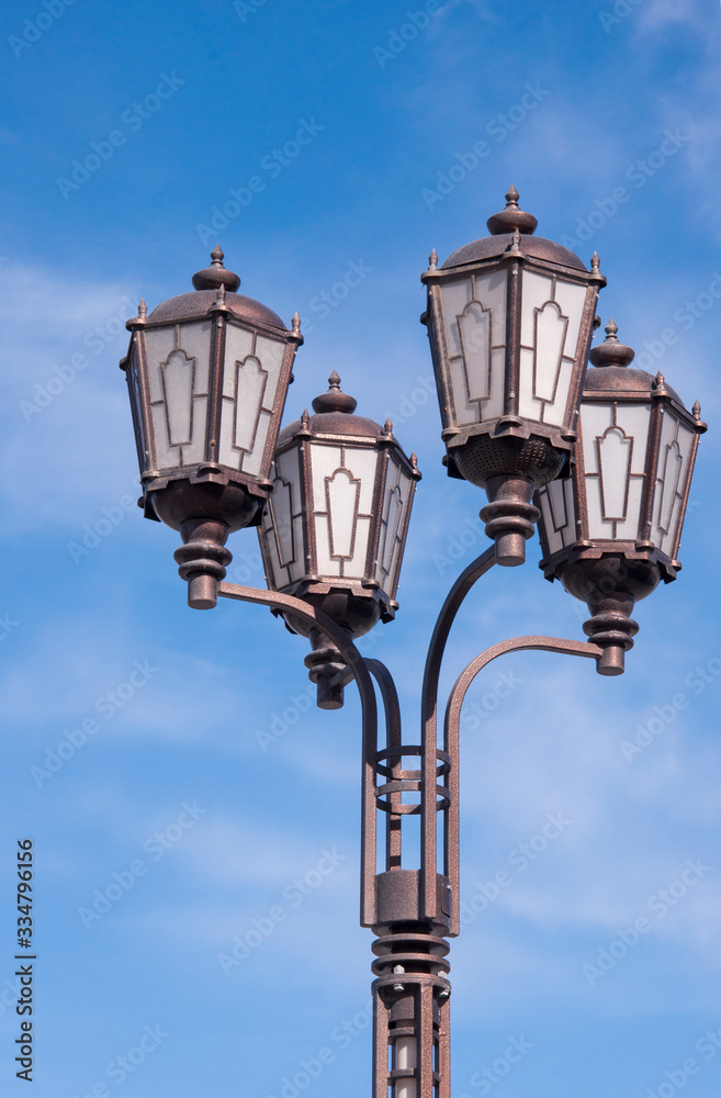 one large vintage lamppost closeup against a blue sky