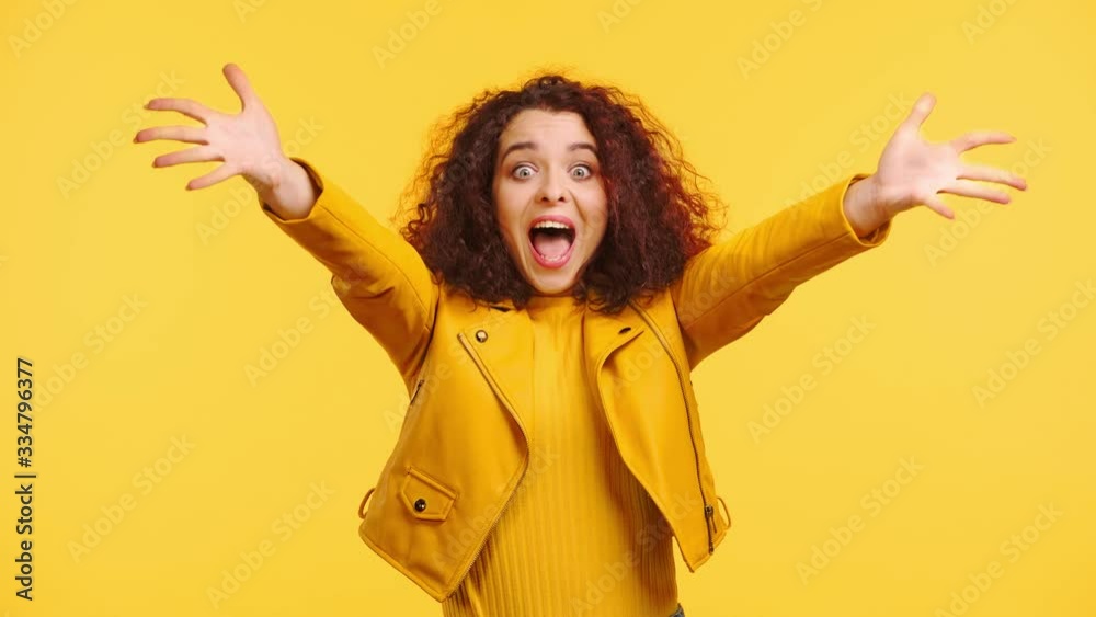 excited, happy girl holding crossed fingers and gesturing isolated on yellow