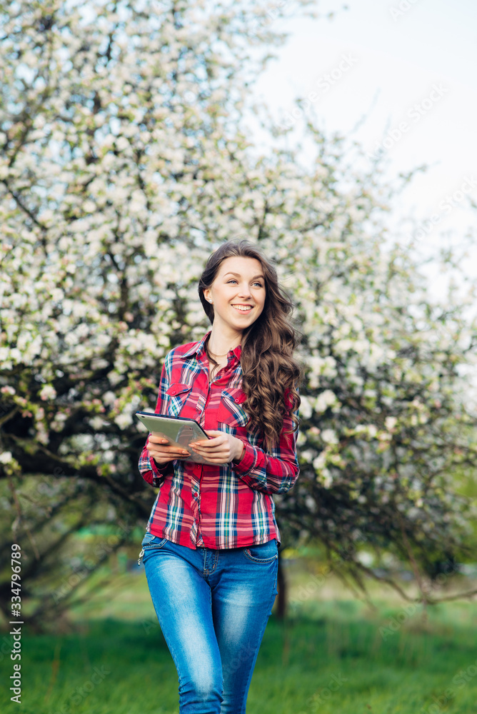 Attractive woman with tablet in blooming garden