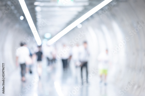 Abstract blurred modern subway station tunnel interior with people walking. Blur underground or metro pedestrian walkway background. Use for backdrop or design element in public transportation concept