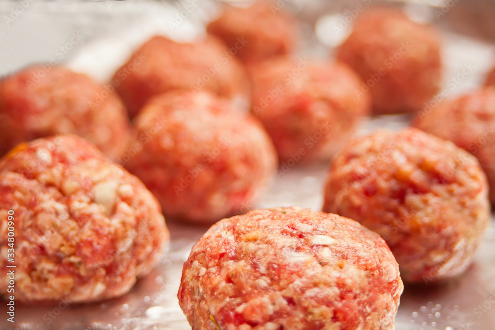 Row of raw meat balls on the foil. Row of raw meat balls on the foil.