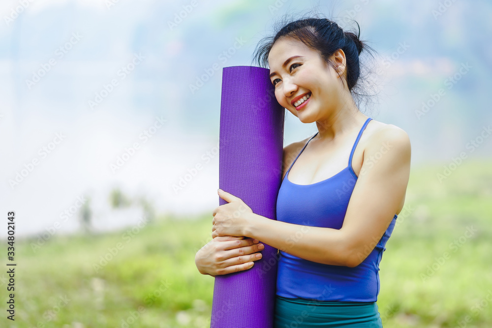 Young asian woman wearing exercise suit with yoga mat or fitness mat after practicing yoga in park. Healthy and Fitness concept Young asian woman wearing exercise suit with yoga mat or fitness mat after practicing yoga in park. Healthy and Fitness concept