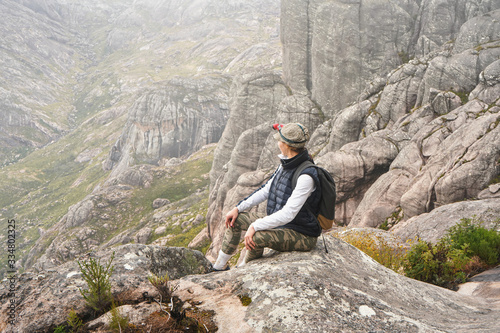 Young woman in sports clothing sitting on rocks enjoying the scenery of Andringitra national park, large stones massif background, during hike to pic Boby peak