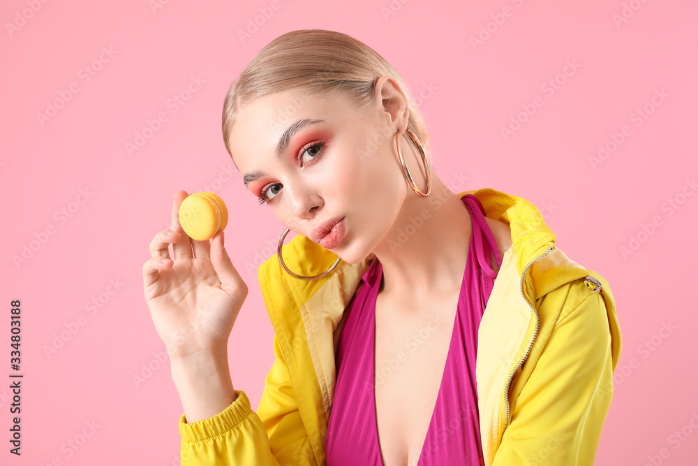 Beautiful fashionable woman with macaron on color background Beautiful fashionable woman with macaron on color background