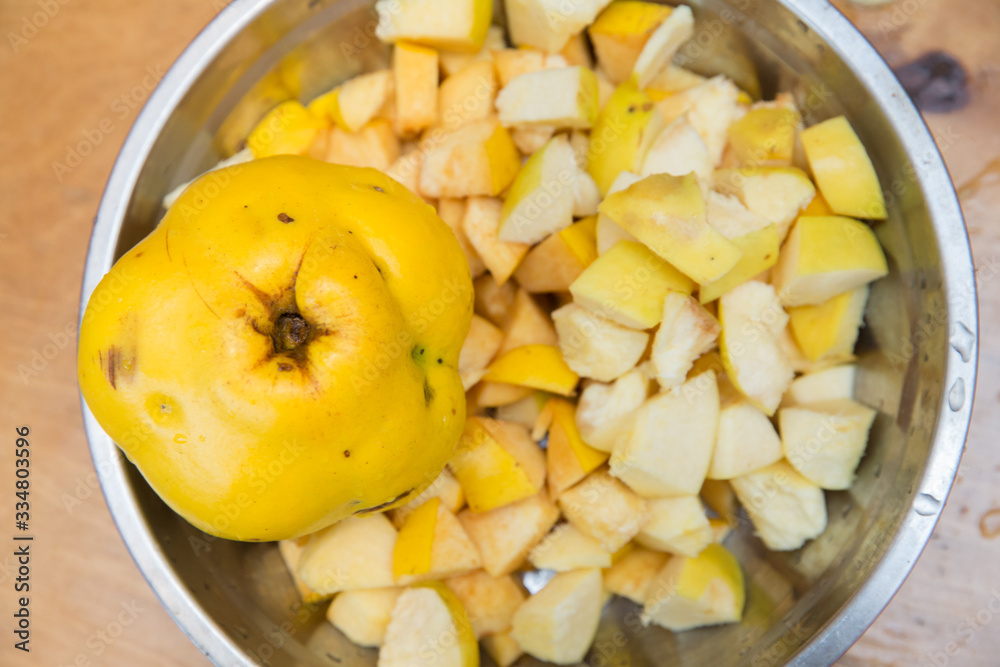 standing on a wooden chopping board . Quince fruit is cut into large pieces, composed in metallic heat resistant pot, bake, standing on a wooden chopping board . Quince fruit is cut into large pieces, composed in metallic heat resistant pot, bake,