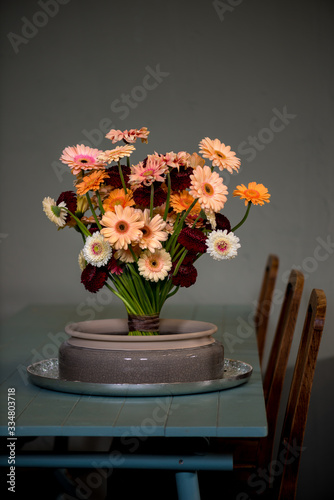 flowerdesign woth gerbera flowers in shades of orange and pink on a wooden table