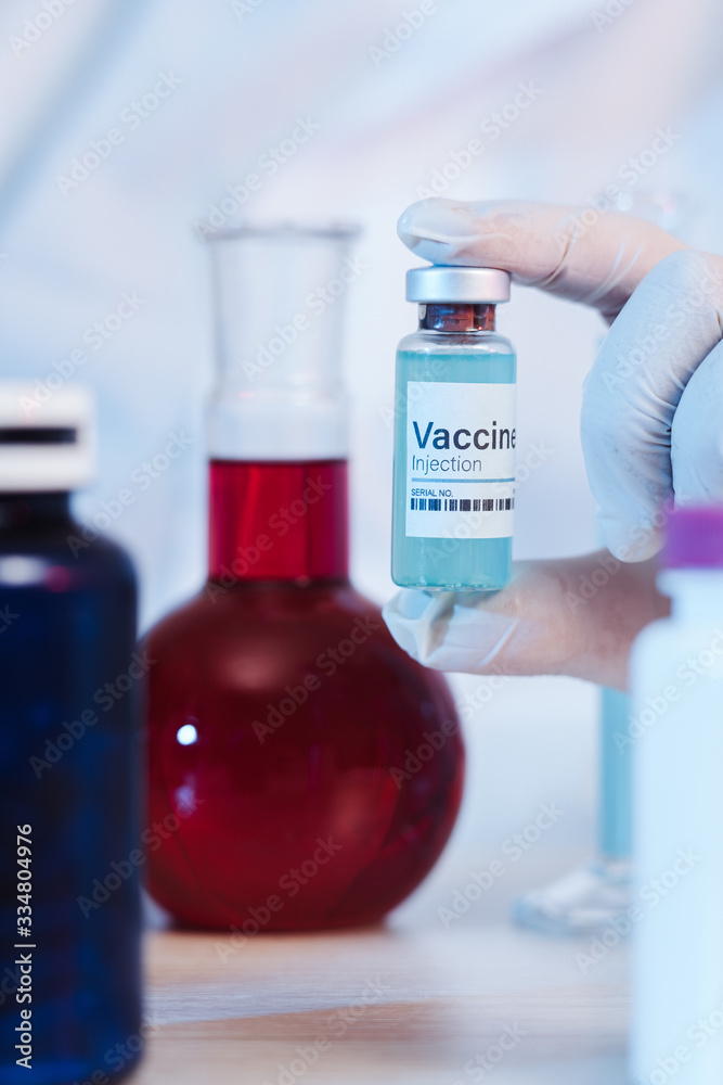 Glass medical bottle in a doctor's hand. A bottle with a medicine holds a hand in silicone gloves in a hospital. The nurse prepares the vaccine. A breakthrough in treatment. Antiviral vaccination. Glass medical bottle in a doctor's hand. A bottle with a medicine holds a hand in silicone gloves in a hospital. The nurse prepares the vaccine. A breakthrough in treatment. Antiviral vaccination.
