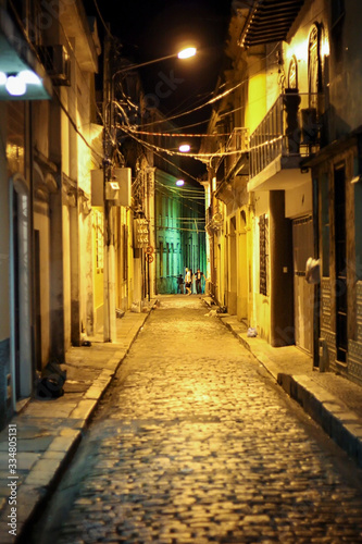 Rua muito antiga de Belém, PA, com pessoas distantes e postes com luz amarela