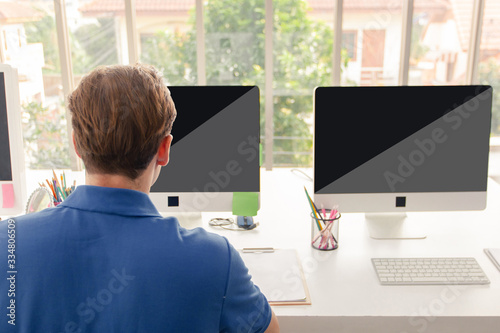 Young man working on his laptop with blank copy space screen for your advertising text message in office, Man sitting at his desk and working in bright modern office
