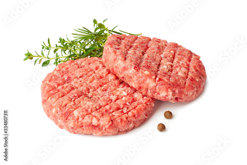 Fotografie Two raw burger patties with thyme and reosemary on white